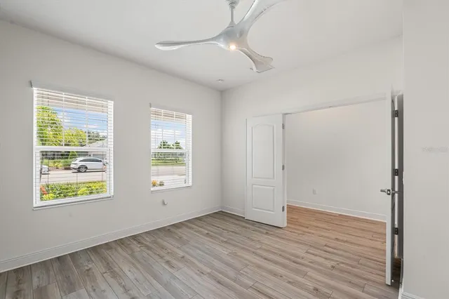 a view of an empty room with wooden floor and a window