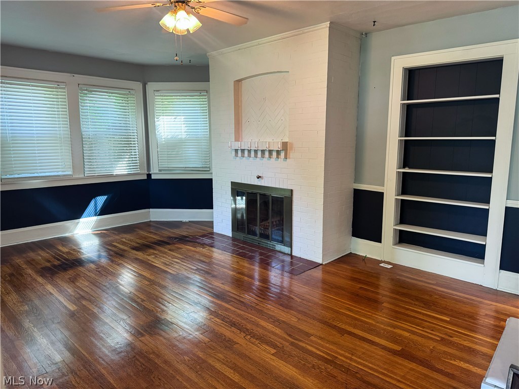 7121 North Lima Road Youngstown, OH 44514 - Photo 8 of 37 Spacious room featuring rich wood-finish flooring, a white brick fireplace with a metallic insert, and built-in shelving