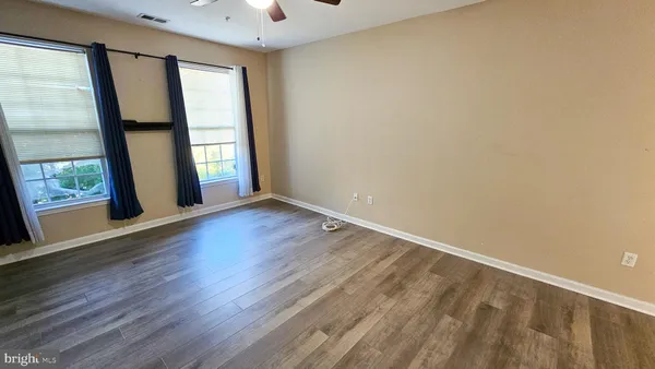 an empty room with wooden floor and windows