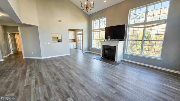 an empty room with wooden floor fireplace and windows