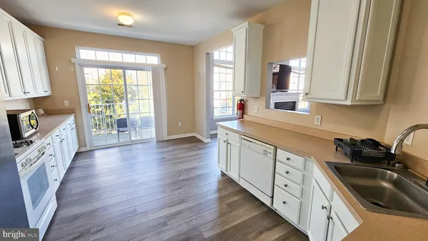 a kitchen with granite countertop a sink dishwasher stove and wooden cabinets