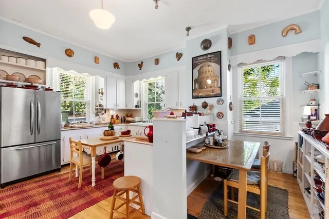 a kitchen with a refrigerator a stove a dining table and chairs with wooden floor