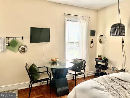 a bedroom with a bed a flat screen tv and chairs