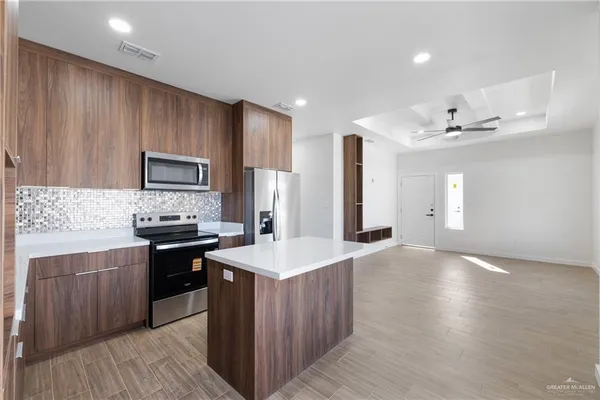 a kitchen with kitchen island granite countertop wooden cabinets a refrigerator and a sink
