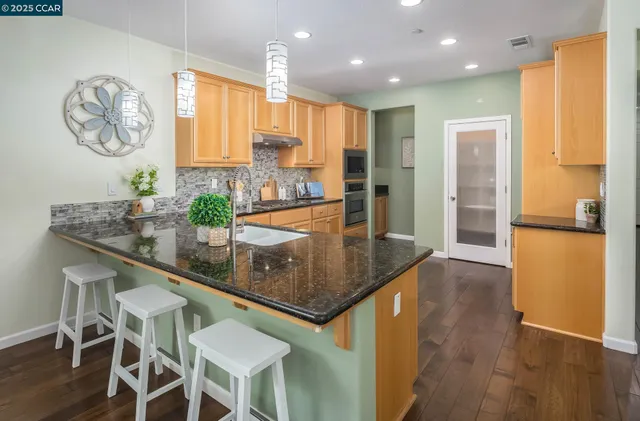 a kitchen with stainless steel appliances granite countertop a kitchen island a stove a cabinets and a dining table
