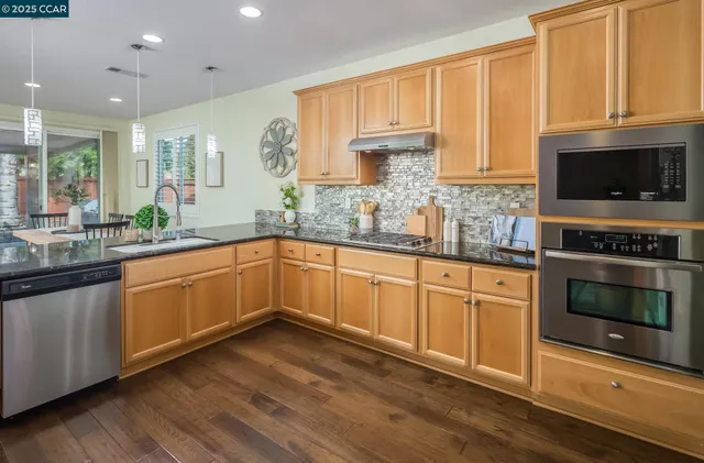 a kitchen with granite countertop a stove a sink and a microwave