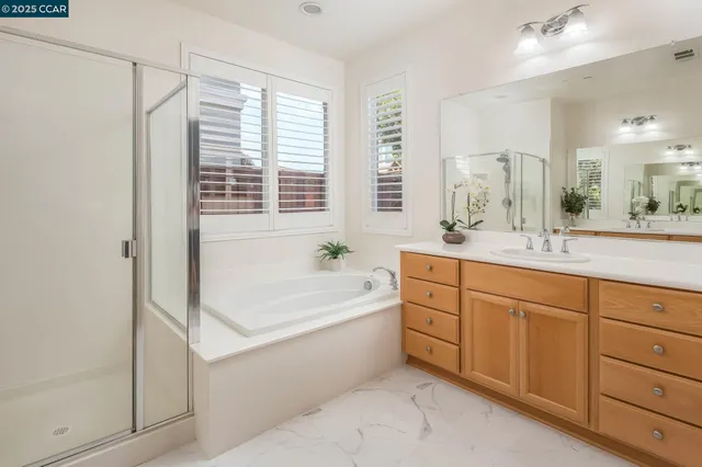 a spacious bathroom with a double vanity sink a large mirror and a bathtub