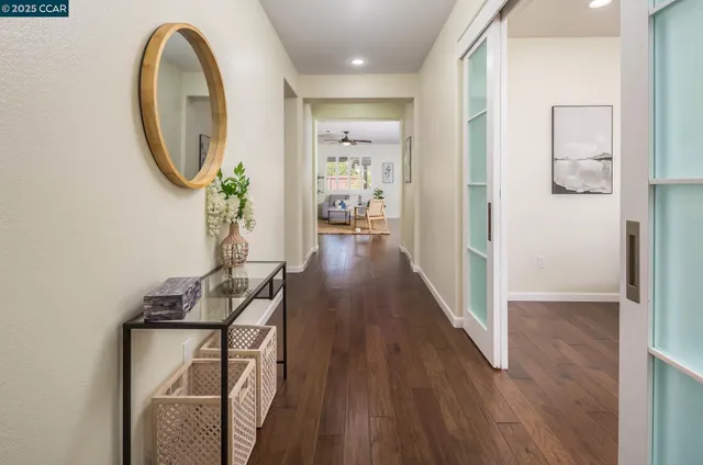a view of a hallway with wooden floor and a dining room