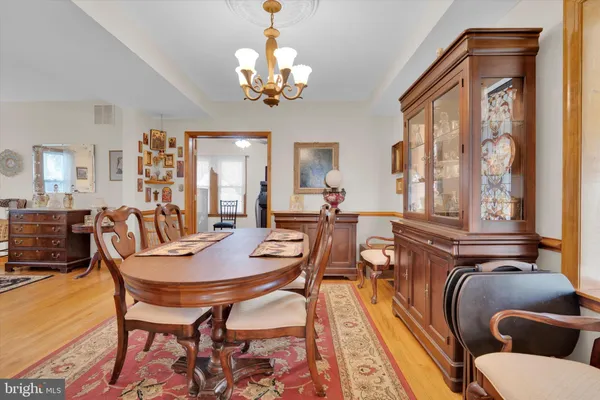 a dining room with wooden floor a chandelier a wooden table and chairs