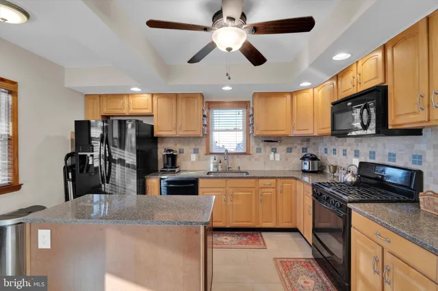 a kitchen with stainless steel appliances granite countertop a refrigerator a stove a microwave a sink dishwasher and white cabinets with wooden floor