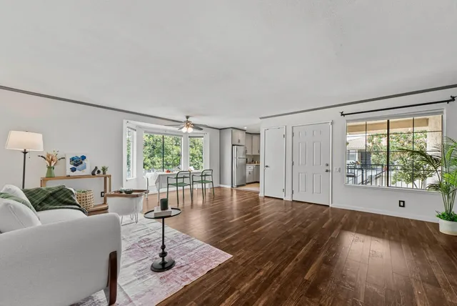 a living room with furniture large window and wooden floor