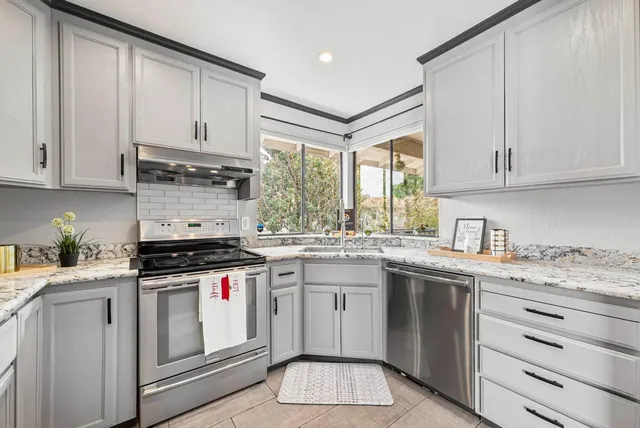 a kitchen with stainless steel appliances granite countertop a stove a sink and white cabinets