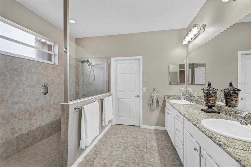 19792 Cobblestone Circle Venice, FL 34292 - Photo 19 of 36 a bathroom with a double vanity sink a large mirror and shower