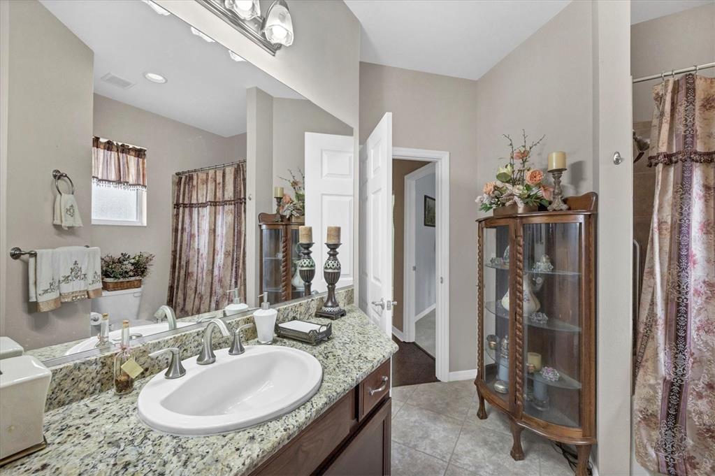 19792 Cobblestone Circle Venice, FL 34292 - Photo 25 of 36 a bathroom with a granite countertop sink a mirror and a shower