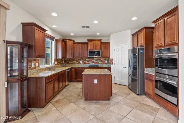 a kitchen with stainless steel appliances granite countertop wooden cabinets a sink and dishwasher with wooden floor