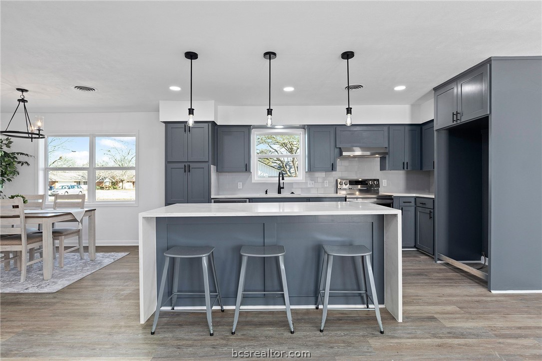 a kitchen with kitchen island granite countertop a sink and a refrigerator