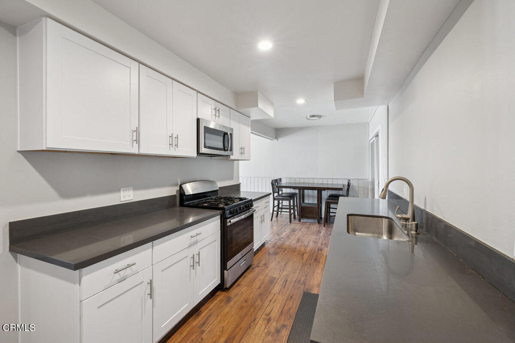 1841 South F Street Oxnard, CA 93033 - Photo 8 of 27 a kitchen with stainless steel appliances granite countertop a stove a sink a refrigerator and white cabinets with wooden floor