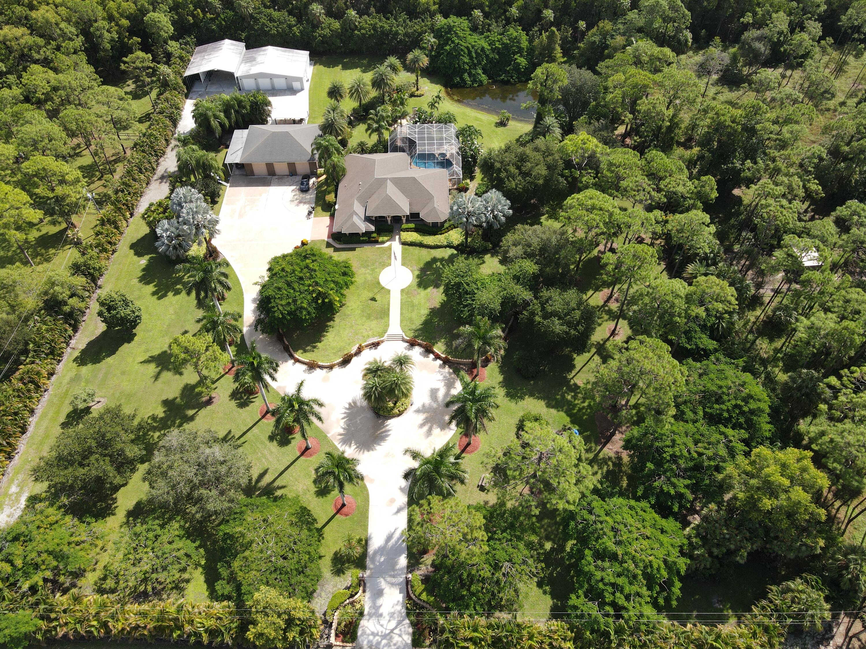 an aerial view of residential house with outdoor space and trees all around
