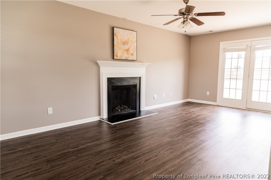 125 Cape Fear Road Raeford, NC 28376 - Photo 6 of 46 an empty room with wooden floor a ceiling fan and windows