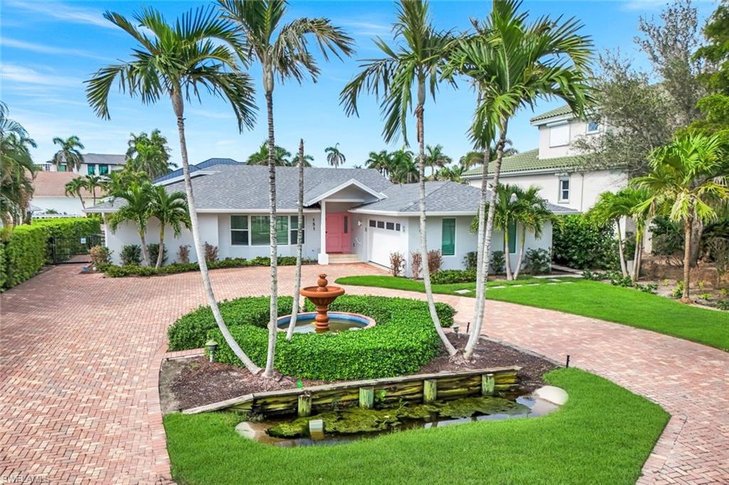 a front view of a house with garden and trees