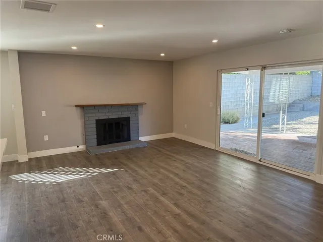 an empty room with wooden floor and fireplace