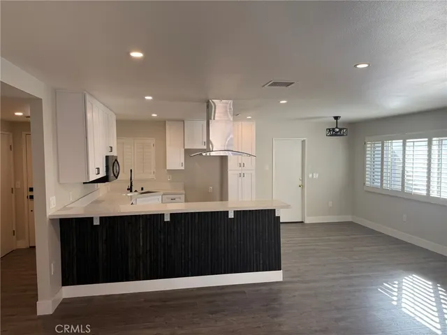 a kitchen with stainless steel appliances granite countertop a sink dishwasher a refrigerator and white cabinets with wooden floor