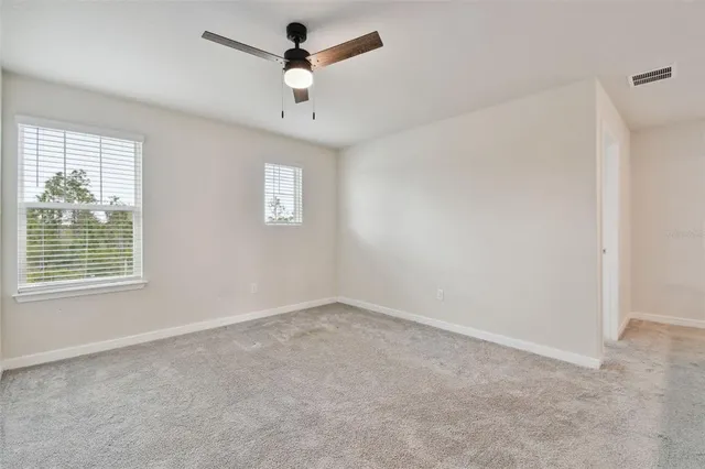 a view of a room with window a ceiling fan and a kitchen view