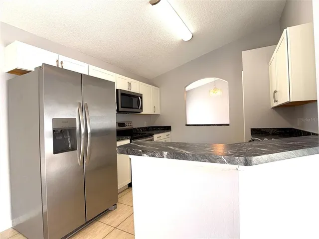 a kitchen with stainless steel appliances granite countertop a refrigerator a stove and a sink