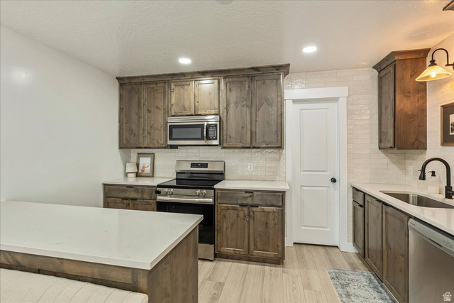 3916 South Sage Wood Avenue Mapleton, UT 84664 - Photo 10 of 33 Kitchen featuring wood-finish cabinetry, stainless steel appliances, light countertops, and a subway tile backsplash
