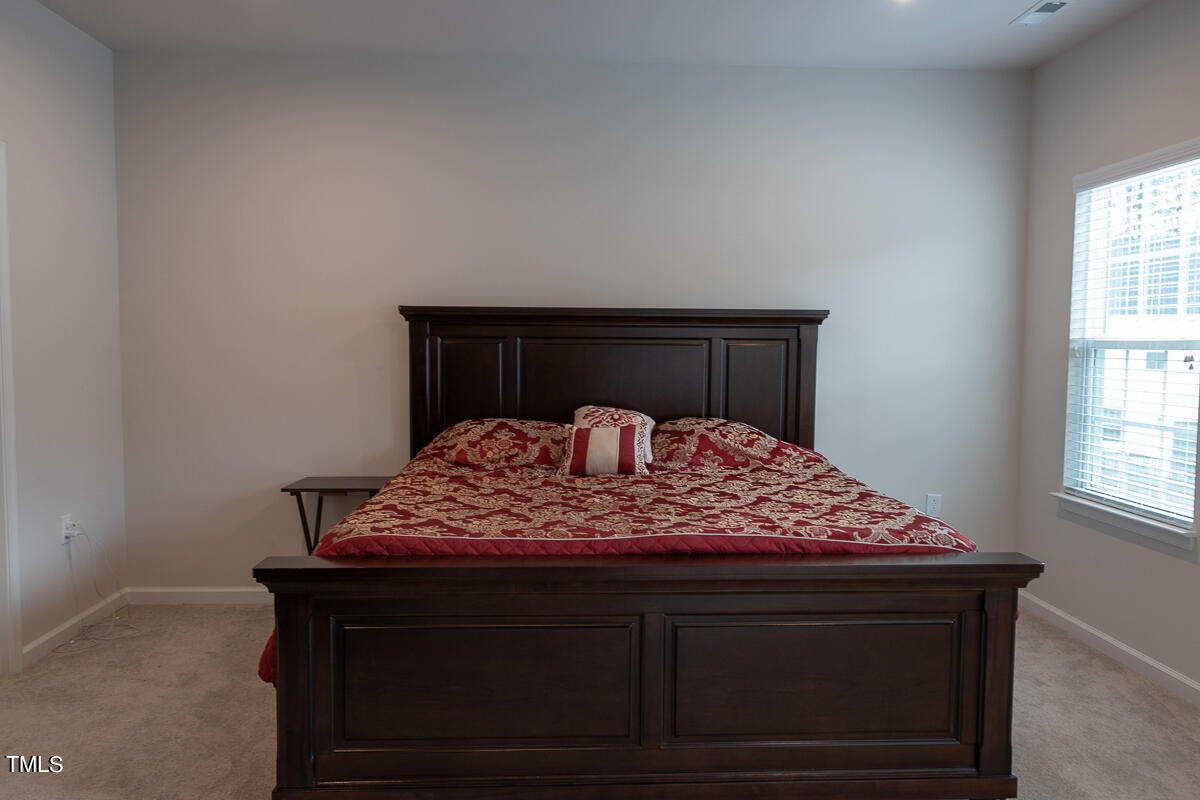 1505 Newpoint Drive Durham, NC 27713 - Photo 25 of 48 a bed sitting in a bedroom next to a window with lamp