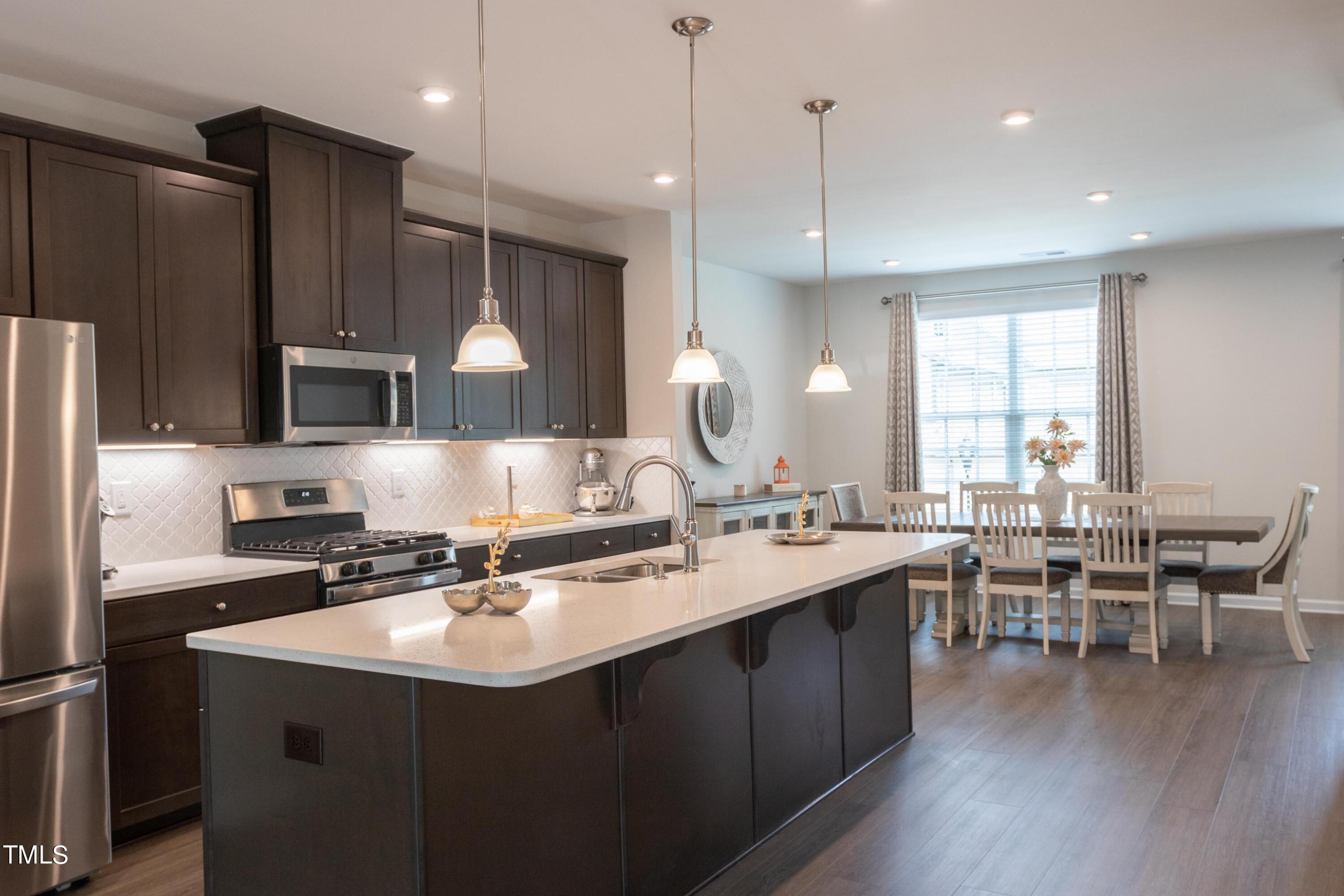 1505 Newpoint Drive Durham, NC 27713 - Photo 4 of 48 a kitchen with stainless steel appliances granite countertop a sink dishwasher a refrigerator and a dining table with wooden floor