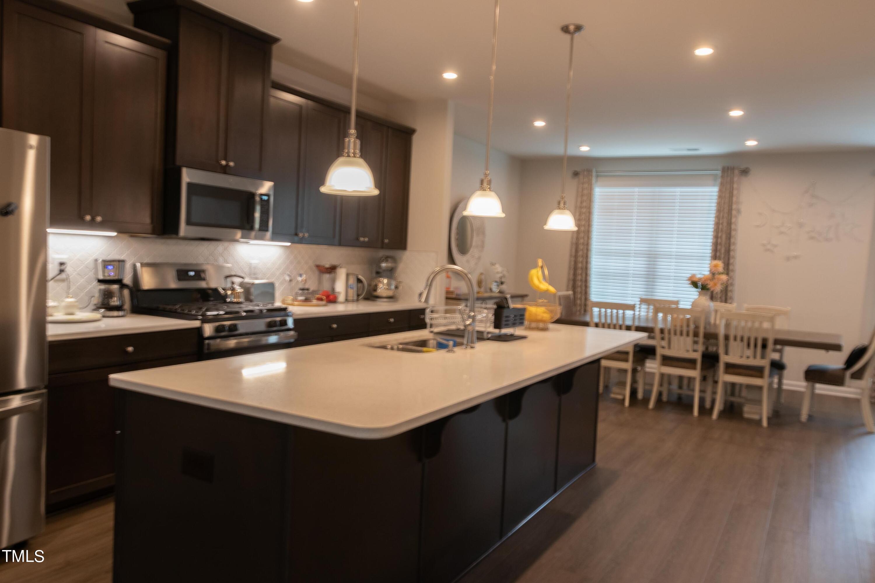 1505 Newpoint Drive Durham, NC 27713 - Photo 5 of 48 a kitchen with kitchen island a sink and a stove top oven with wooden floor