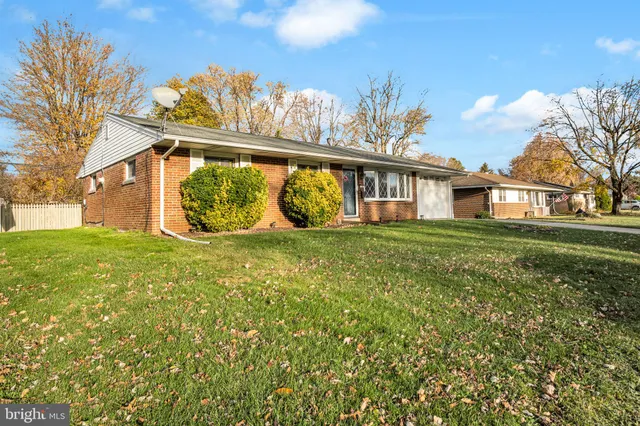 a view of house with a big yard and large trees