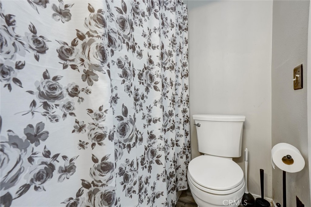 4687 Knickerbocker Lane Riverside, CA 92501 - Photo 17 of 27 a white toilet sitting next to a shower curtain