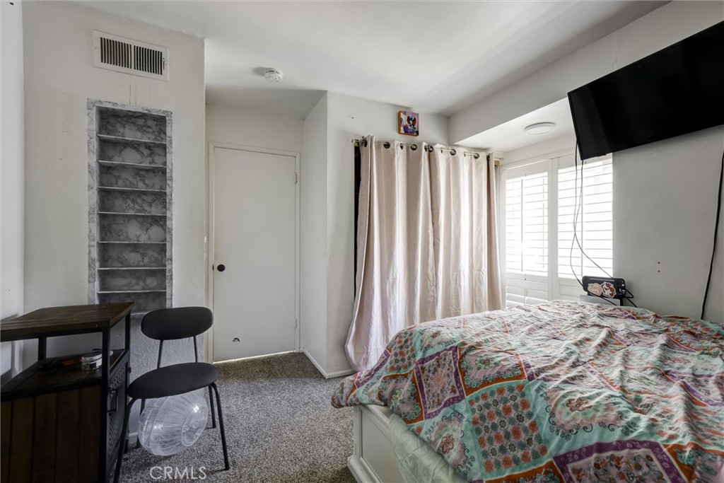 4687 Knickerbocker Lane Riverside, CA 92501 - Photo 19 of 27 a bedroom with a bed a flat screen tv and a large window