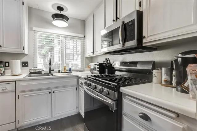 a kitchen with cabinets appliances a sink and a window