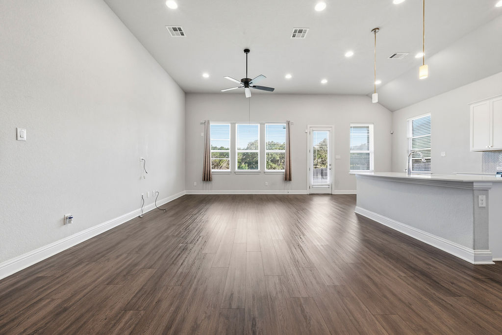 2032 Base Burner Path Leander, TX 78641 - Photo 11 of 34 Open-concept living area featuring wood-finish flooring, vaulted ceiling with recessed lighting, ceiling fan, and multiple windows
