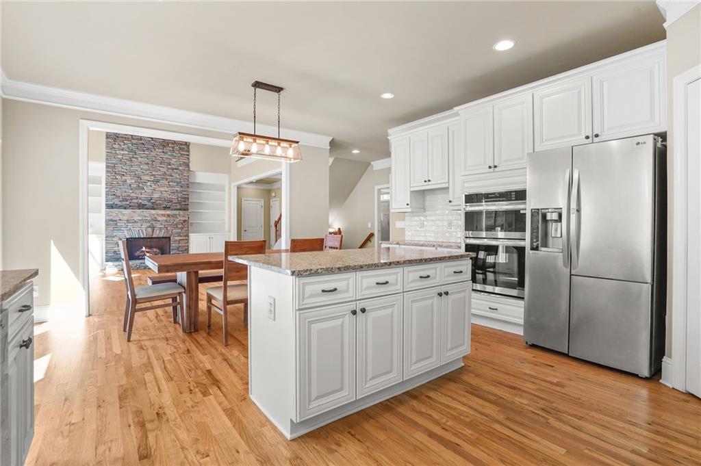 955 Gardiner Circle Suwanee, GA 30024 - Photo 15 of 44 a kitchen with stainless steel appliances granite countertop a refrigerator a stove top oven a sink dishwasher and white cabinets with wooden floor