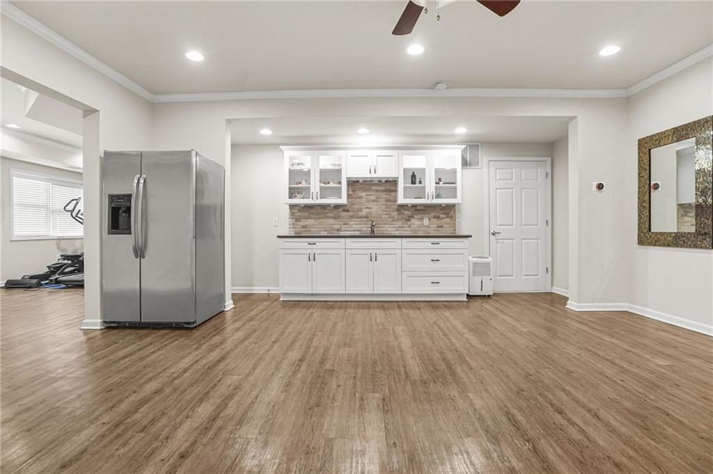 955 Gardiner Circle Suwanee, GA 30024 - Photo 35 of 44 an empty room with wooden floor and a kitchen