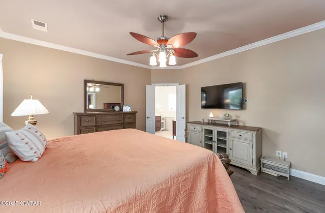 a bedroom with a bed and a flat tv screen on dresser