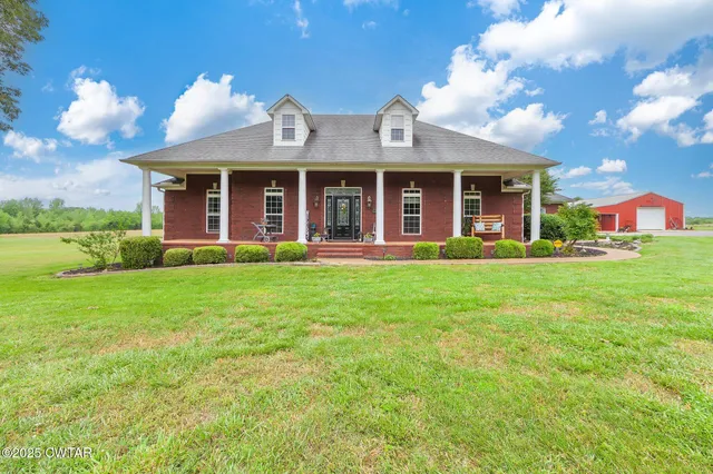 a front view of a house with garden and trees
