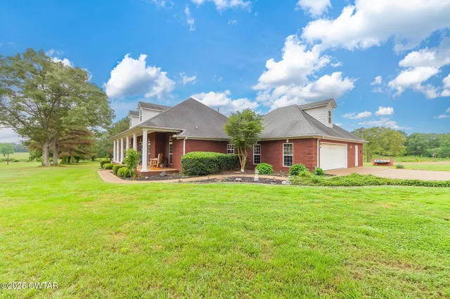 a view of a house with a big yard plants and large trees