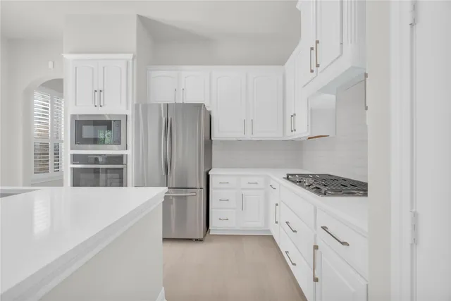 a kitchen with stainless steel appliances a refrigerator stove and white cabinets