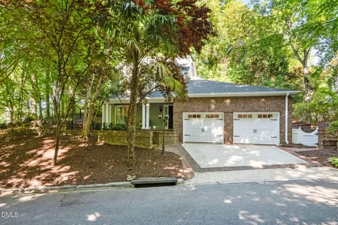 a front view of a house with a garden and trees