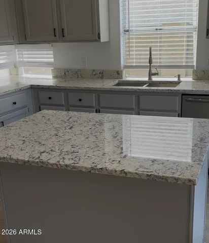 a bathroom with a granite countertop sink a window and a counter top