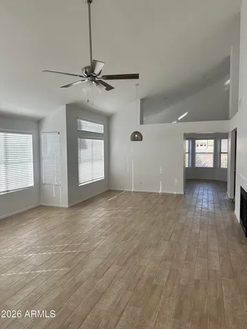 a view of empty room with wooden floor and fan