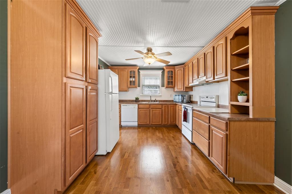710 South Old Temple Road Lorena, TX 76655 - Photo 7 of 19 Kitchen featuring white appliances, dark wood-style flooring, glass fronted cabinets, open shelves, and a ceiling fan