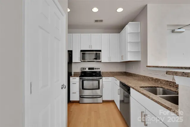 a kitchen with white cabinets appliances and sink