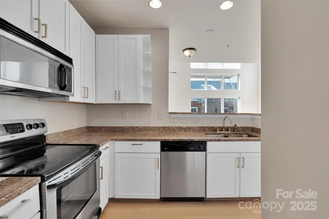 a kitchen with stainless steel appliances granite countertop a stove a sink and a microwave