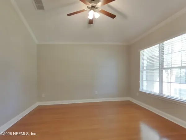 an empty room with windows and fan